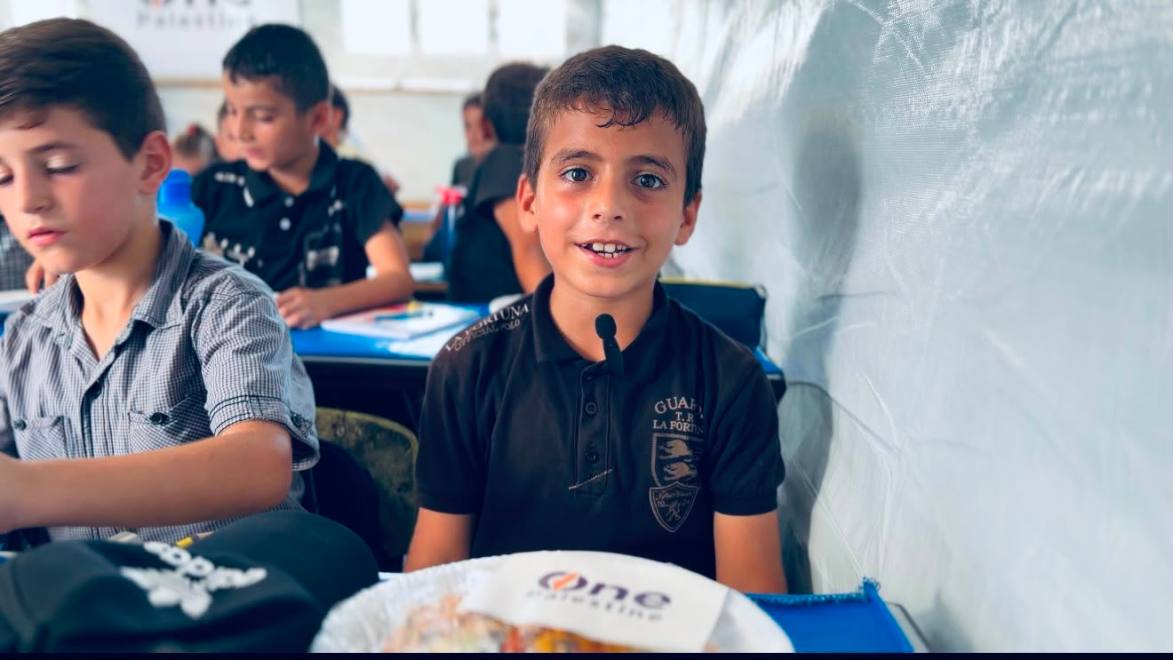 A boy in a Gaza classroom eating during One Palestine Pizza Day